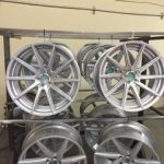Silver powder coated wheels hanging from drying frame